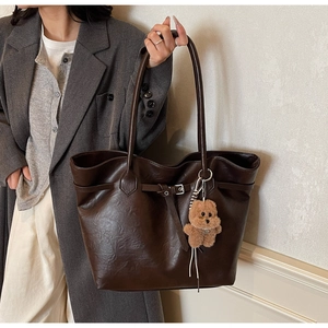 Deep brown tote bag with lychee texture and cute bear charm shown on a shoulder