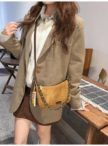 Close-up of brown suede crossbody bag with vintage gold chain and beaded tassel charm