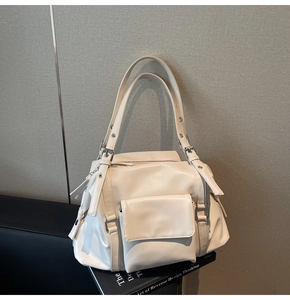 Detail of cream white tote bag featuring side decorative zippers and multiple utility pockets