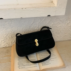 Detail of minimalist black suede shoulder bag featuring a sleek oval gold metal buckle