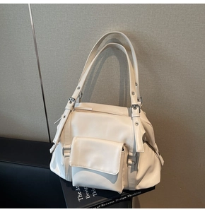 Detail of cream-colored tote bag featuring silver buckles and a front flap pocket