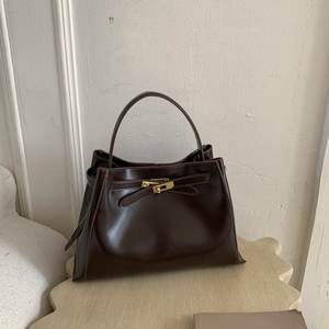 Detailed view of the gold-tone rotating metal lock and buckle on a brown leather handbag