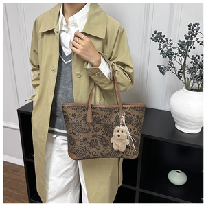 Close-up of vintage paisley tote bag with cute plush bear charm on shoulder strap