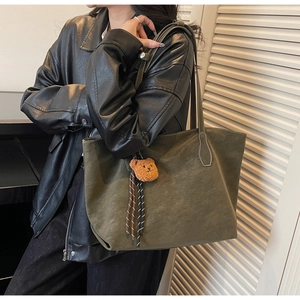 Vue latérale du sac fourre-tout oversize vert olive en daim avec breloque d'ours
