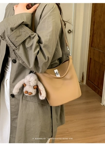 Sac seau chic en cuir beige clair avec fermoir rotatif argenté et breloque lapin doux