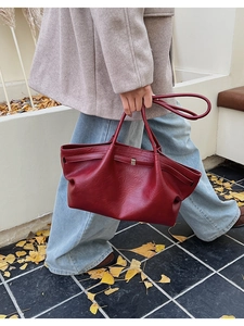 Détail du grand sac cabas en cuir bordeaux montrant la texture et la boucle décorative