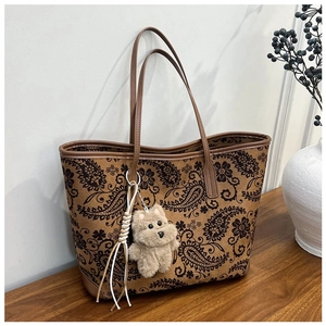 Detail of vintage paisley tote bag featuring brown leather trim and cute plush puppy charm