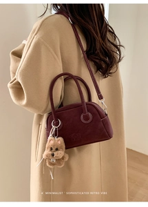 Borsa Boston retrò bordeaux in pelle scamosciata indossata su cappotto cammello con ciondolo