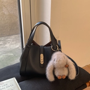 Detail of black lychee grain leather tote bag with silver lock and grey rabbit charm