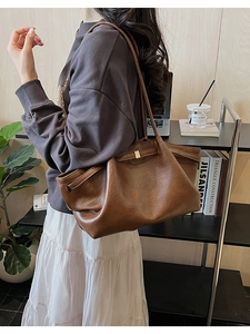 Gros plan du sac cabas en cuir marron avec boucle dorée et fines bretelles d'épaule
