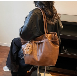 Detail of brown faux leather tote bag with vintage texture and plush bear pendant