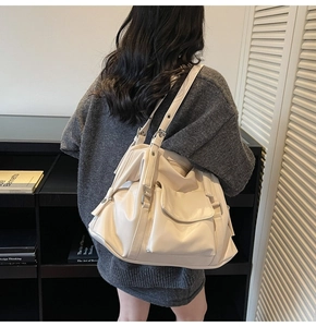 Model view showing the back side of a large cream leather tote bag with soft pleats