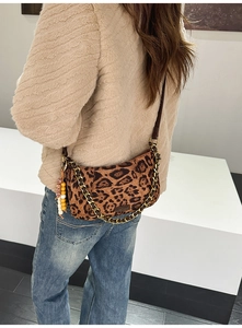 Detail of leopard print suede crossbody bag with metal chain strap and tassel charm