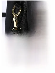 Detail of durable gold metal hooks and smooth zipper on a black lychee texture bag