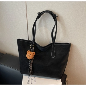 Détail du cabas noir avec surpiqûres blanches et pendentif ours en peluche marron