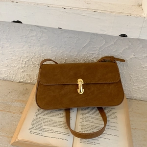 Detailed close-up of brown suede rectangular shoulder bag with golden capsule metal lock