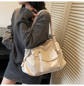 Detail view of cream oversized tote bag with multiple pockets and adjustable metal buckle