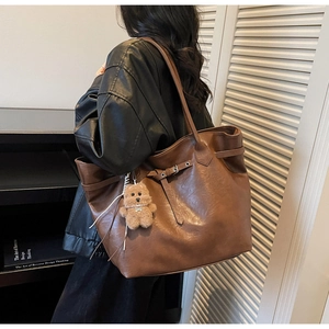 Detail of a large brown tote bag with premium texture and a cute plush bear charm