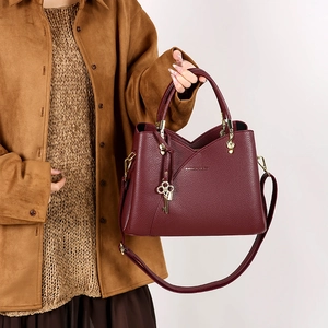 Detail of burgundy lychee pattern shoulder bag with gold hardware and key pendant