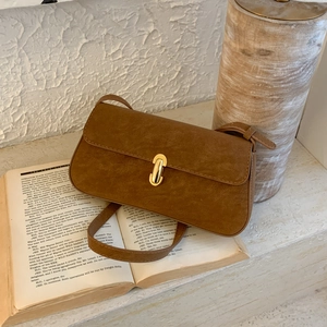 Macro detail of brown suede crossbody bag with vintage gold metal twist lock buckle