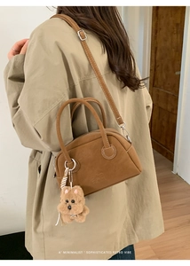 Borsa Boston marrone scamosciata con ciondolo a cane e tracolla removibile su trench