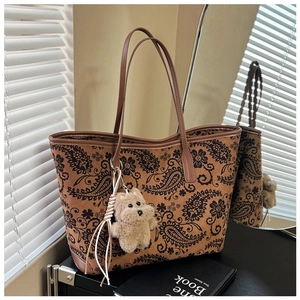 Detail view of vintage paisley print tote bag with brown leather handles and puppy charm