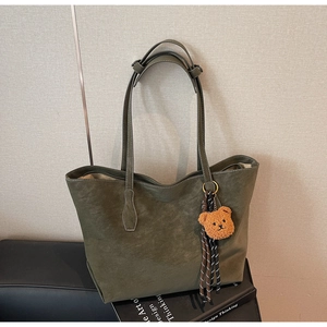 Détail du cabas mat vert olive foncé avec pendentif ours en peluche et lanières tissées