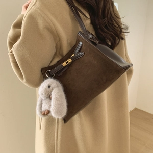 Detail of vintage brown bucket bag with metal buckle strap and plush bunny charm