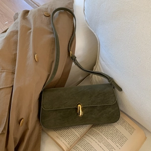 Detail of dark green suede underarm bag with elegant gold metal buckle and matte texture