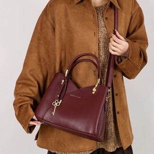 Close-up of burgundy pebbled leather handbag featuring V-cut and gold key charm