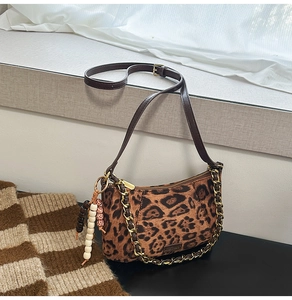 Detail of leopard print suede bag featuring golden chain and beaded tassel charm