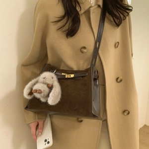 Detail of dark brown suede crossbody bag with gold metallic twist lock and bunny charm