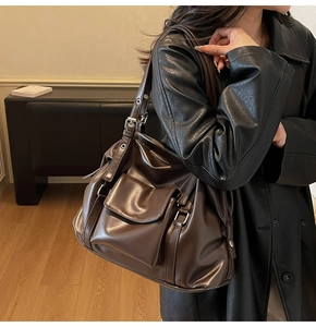Detail of dark brown leather tote bag with silver buckle strap and front flap pocket