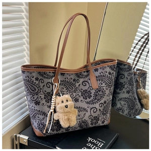 Detail of vintage grey floral tote bag with brown leather handles and plush bear charm