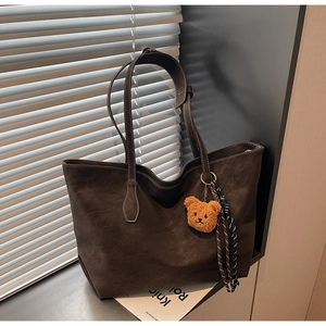 Détail du sac cabas en daim marron avec surpiqûres blanches et pendentif en peluche