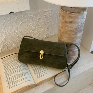 Close-up of olive green suede shoulder bag featuring a polished oval gold clasp detail