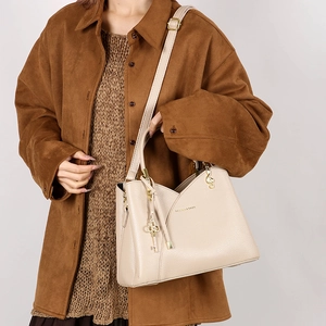 Detail of beige bucket bag with lychee texture and golden musical note pendant