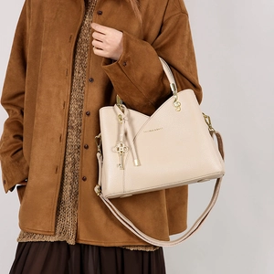 Beige bucket bag with lychee grain texture, V-stitch design and gold tassel detail