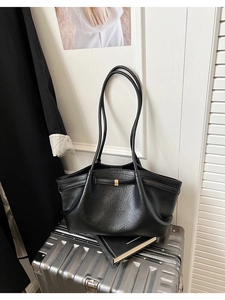 Détail d'un grand sac cabas noir au design plissé avec boucle métallique sur une valise