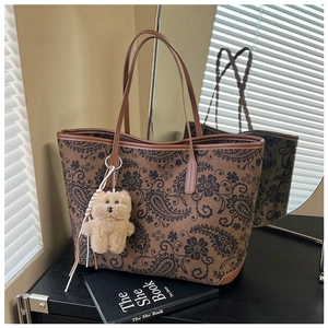 Detail of vintage paisley print tote bag with brown handles and plush bear charm
