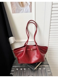 Détail d'un sac cabas rouge avec texture grainée et boucle en métal sur une valise