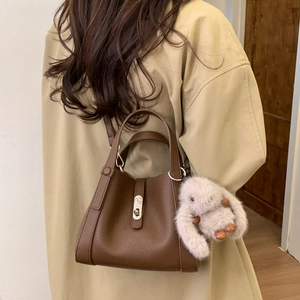 Brown litchi leather bucket bag with metallic twist lock and plush rabbit charm