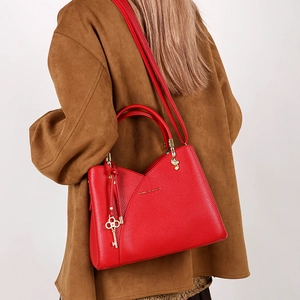 Macro view of red lychee textured leather bucket bag with elegant golden key pendant accessory