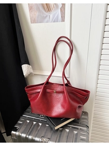 Détail du sac cabas rouge en similicuir avec boucle dorée sur une valise argentée