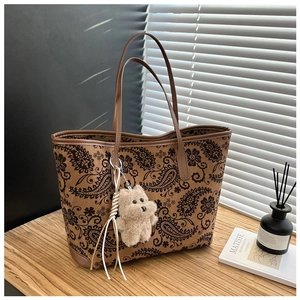 Detail of vintage paisley print tote bag with cute plush puppy charm on wooden table