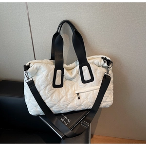 Detail view of white quilted gym bag with black wide straps and adjustable shoulder strap