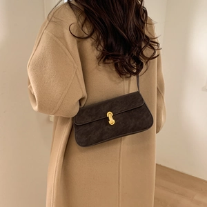 Detail of vintage brown suede shoulder bag with gold buckle on a camel wool coat