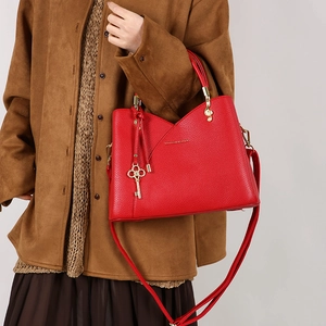 Detail of red leather tote bag with gold key charm and musical G-clef hook detail