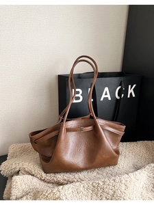Détail de sac cabas marron foncé avec texture cuir grainé et boucle métallique décorative