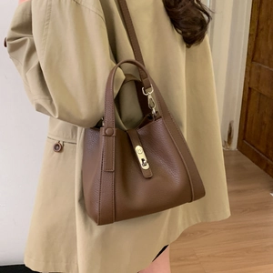 Close-up of brown litchi pattern leather bucket bag with gold metal twist lock and handle